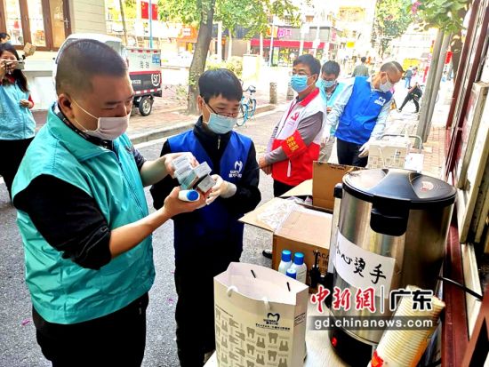 穗华口腔医院医务人员与赵广军生命热线志愿者一起给江南中街道青凤社区值班人员发放防疫物资。(肖金 摄影)